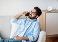 Handsome Eastern Man Talking On Cellphone While Relaxing On Sofa At Home Royalty Free Stock Photo