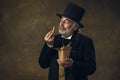 Handsome elderly gray-haired man, gentleman, aristocrat or actor eating fast food isolated on dark vintage background Royalty Free Stock Photo