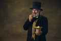 Handsome elderly gray-haired man, gentleman, aristocrat or actor eating fast food isolated on dark vintage background Royalty Free Stock Photo