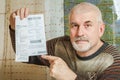A handsome elderly man shows a receipt