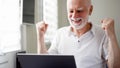 Handsome elderly senior man working on laptop computer at home. Received good news excited and happy Royalty Free Stock Photo