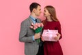 Handsome elegant man in classic suit giving flowers and gift box to his beautiful girlfriend Royalty Free Stock Photo