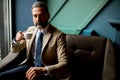 Handsome elegant serious businessman sitting in armchair and holding cup of espresso. Royalty Free Stock Photo