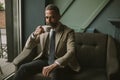 Handsome elegant serious businessman sitting in armchair and holding cup of espresso. Royalty Free Stock Photo