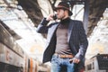 Handsome elegant young hispanic man holding smart phone in his hand and calling while he standing at the railway Royalty Free Stock Photo