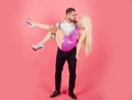 Handsome elegant young man holding his girlfriend in his arms. Creative dolls couple concept. Strong funny man holds and Royalty Free Stock Photo