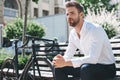 Handsome elegant young man sits on the bench and relax and thinking in the public garden Royalty Free Stock Photo