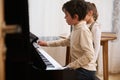 Handsome kids a teenage boy and little child girl, playing grand piano together during a music lesson at home. Royalty Free Stock Photo