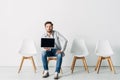 Handsome employee holding laptop with blank screen