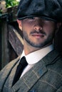 Handsome English gangster dressed in waistcoat and jacket sitting and looking at camera