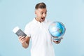 Handsome excited happy adult man posing isolated over blue wall background holding passport with tickets and globe Royalty Free Stock Photo