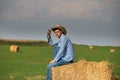 Farmer sitting on straw bale roll in field