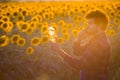 Handsome farmer standing in the middle of a golden sunflower field talking on phone while holding up a sunflower oil bottle during Royalty Free Stock Photo