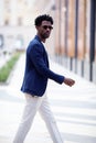 Handsome fashion African American man walks down the street in stylish attire white pants, blue blazer. Fashionable Royalty Free Stock Photo