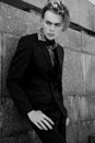 Handsome fashion male model dressed in elegant suit posing outdooe. Long haired Metrosexual. Black and white picture.