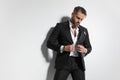 Handsome fashion model arranging his tuxedo and looking down Royalty Free Stock Photo