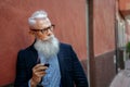 Handsome fashionable senior man with white beard and mustache holding glass of red wine