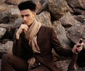 fashionable young man sitting on the rocks near the sea Royalty Free Stock Photo