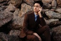 fashionable young man sitting on the rocks near the sea Royalty Free Stock Photo