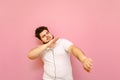 Handsome fat man listening to music in headphones and dancing on a pink background. The overweight charismatic guy dances to music Royalty Free Stock Photo