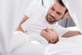 handsome father lying on bed with little