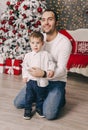 Handsome father playing with his small cute son near decorated New year tree Royalty Free Stock Photo
