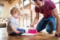 Handsome father and toddler boy with brush and dustpan.