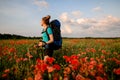 Handsome female tourist stands on field of red poppies. Royalty Free Stock Photo