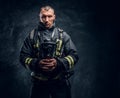 A handsome fireman wearing protective uniform holding an oxygen mask and looking at a camera.