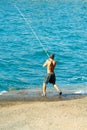 Handsome fisherman fishes with fishing rod in Canary Islands, Spain