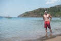 A handsome, fit, tanned, and attractive Filipino man wearing shades and board shorts at the beach. Summertime concept Royalty Free Stock Photo