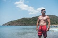 A handsome, fit, tanned, and attractive Filipino man wearing sunglasses and board shorts at the beach. Summertime concept Royalty Free Stock Photo