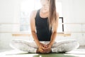 Handsome fit woman doing stretching exercise sitting on yoga mat in sunny white gum