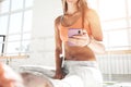 Handsome fit woman sitting on yoga mat and hold smartphone in hand counts calories in fitness application after training