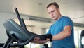 Handsome fit young man in gym doing exercises on exercise bike. Using his smartwatch checking vitals