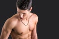 Handsome, fit young man shirtless, against dark background Royalty Free Stock Photo