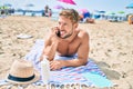 Handsome fitness caucasian man at the beach on a sunny day sunbathing lying on the towel speaking on the phone Royalty Free Stock Photo