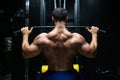 Handsome fitness man is performing back workouts using thrust of the upper block machine in a gym, back view Royalty Free Stock Photo