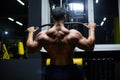 Handsome fitness man is performing back workouts using thrust of the upper block machine in a gym, back view Royalty Free Stock Photo