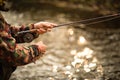 Handsome fly fisherman fly fishing on a splendid mountain river for rainbow trout