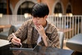 Handsome and focused young Asian man taking notes on a digital tablet, remote working at cafe Royalty Free Stock Photo