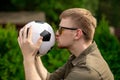 Handsome football fan kisses soccer ball, Happy young man celebrating victory