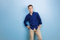 Handsome friendly looking cheerful european guy wearing blue shirt smiling standing over blue wall