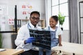 Male doctor pediatrician, showing results of x-ray CT scan for little african kid girl Royalty Free Stock Photo