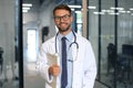 Handsome friendly young doctor on hospital corridor looking at camera, smiling Royalty Free Stock Photo