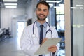 Handsome friendly young doctor on hospital corridor looking at camera, smiling Royalty Free Stock Photo