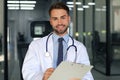 Handsome friendly young doctor on hospital corridor looking at camera, smiling Royalty Free Stock Photo