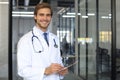 Handsome friendly young doctor on hospital corridor looking at camera, smiling Royalty Free Stock Photo