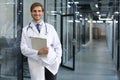 Handsome friendly young doctor on hospital corridor looking at camera, smiling Royalty Free Stock Photo