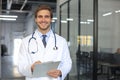 Handsome friendly young doctor on hospital corridor looking at camera, smiling Royalty Free Stock Photo